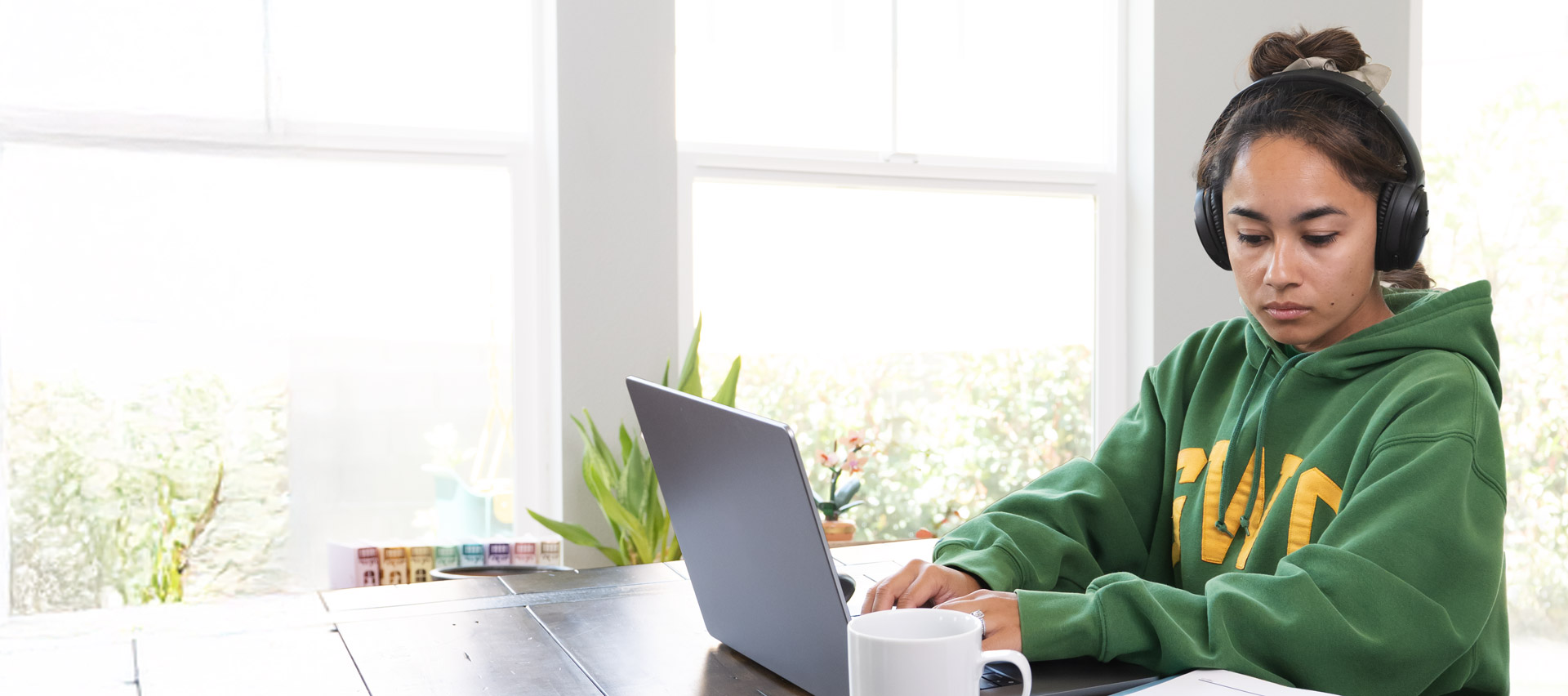 A female student works on her laptop at her kitchen table.